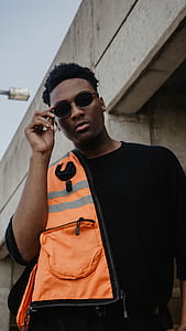 man holding sunglasses standing in front of bridge thumbnail