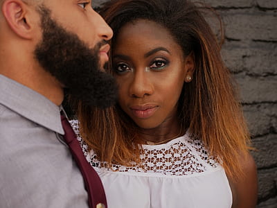 woman beside bearded man taking photo in front of wall at daytime thumbnail