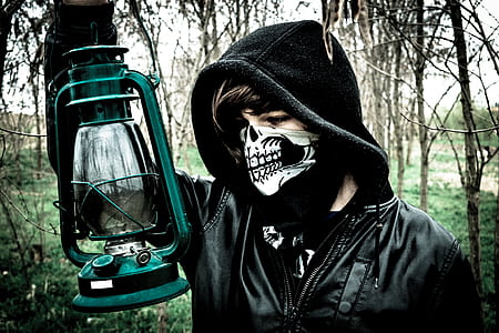 man wearing black hoodie and holding cold-blast lantern near woods outdoors thumbnail