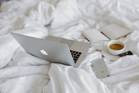 Woman working on a laptop while enjoying a breakfast coffee and chocolate in bed thumbnail
