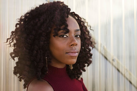 woman wearing red sleeveless top with curly hair at daytime thumbnail