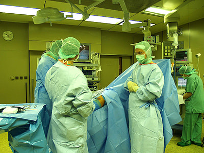 three people standing beside patient lying on bed inside operating room thumbnail