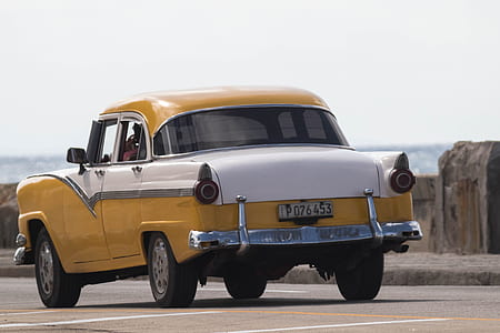 classic yellow and white sedan parked on parking area during daytime thumbnail