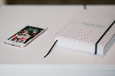gold iPhone 6 beside notebook on white table thumbnail
