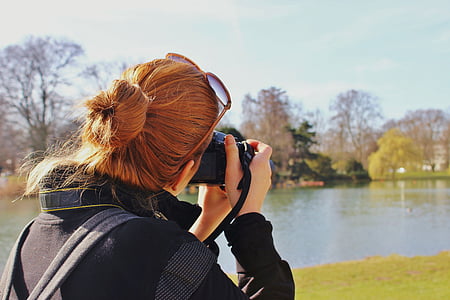 woman in black jacket taking picture of lake thumbnail