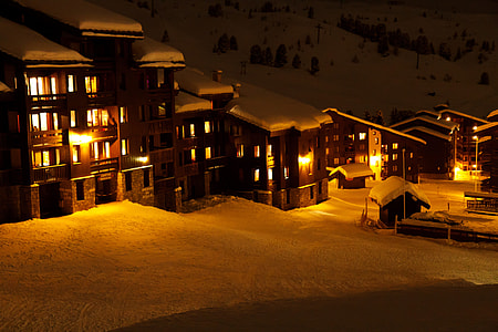 lighted village houses surrounded of snow covered field during nighttime thumbnail