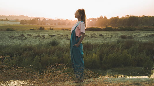 woman in green overalls standing on field thumbnail