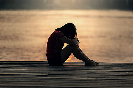 woman sitting in pavement near body of water thumbnail