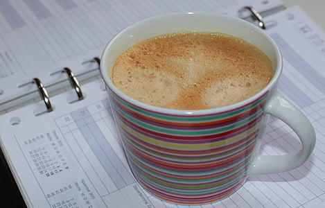 brown liquid filled white and multicolored cup on notebook thumbnail