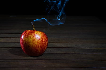 Red Apple With Smoke Coming from Stalk on Wooden Floor thumbnail