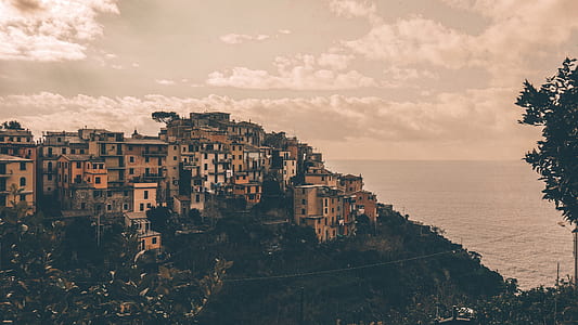 beige concrete buildings on mountain beside body of water thumbnail