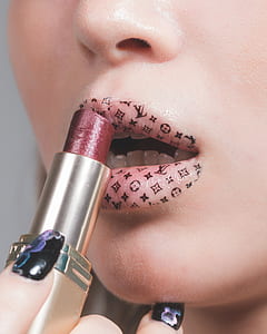 focus photography of woman's lip with Louis Vuitton tattoo and red lipstick thumbnail