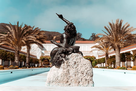 selective focus photography of woman in dress sitting on rock figurine thumbnail