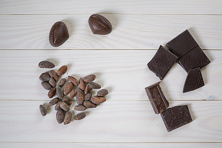 chocolate bar beside peanuts on white wooden surface thumbnail