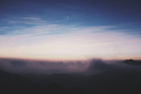 silhouette of mountains covered by clouds during sunset thumbnail