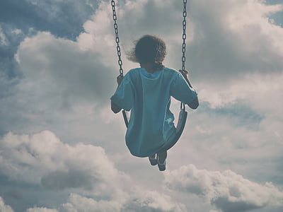 person riding swing under cloudy sky during daytime thumbnail