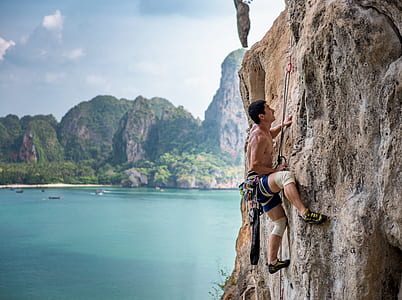 man in black and white shorts climbing cliff during daytime thumbnail