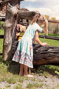 toddler girl standing beside brown bear plush toy leaning on brown bag at daytime thumbnail