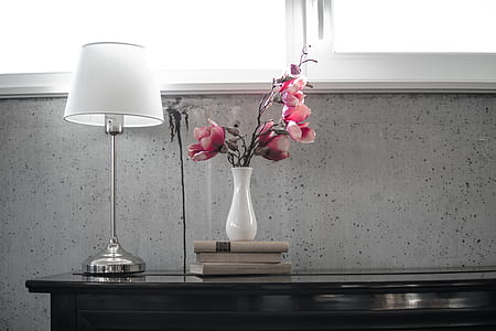 pink Magnolia flowers in vase beside lamp thumbnail