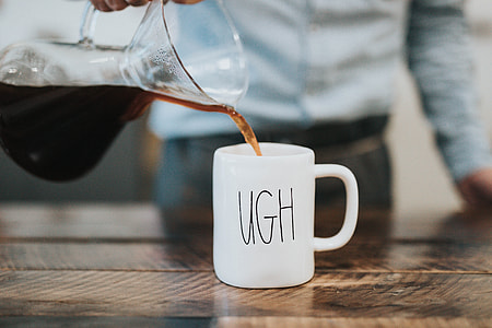 person holding glass pitcher pouring to white ceramic mug thumbnail