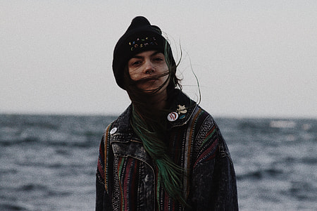 selective focus photo of woman wearing brown and black near sea thumbnail