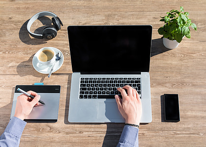 person using MacBook Pro and trackpad on top of brown wooden table thumbnail