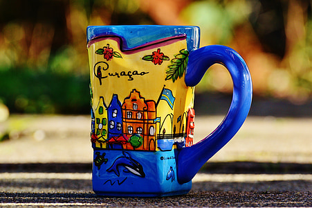 red and yellow ceramic mug on black sand thumbnail