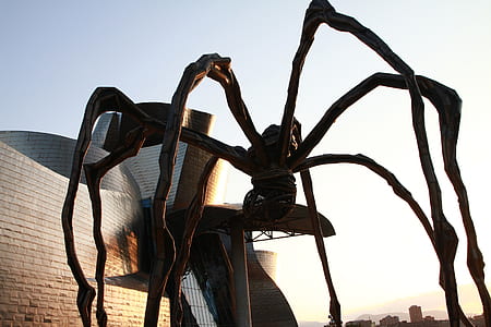 brown spider statue beside gray building at daytime thumbnail