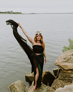 woman standing on stone near body of water during daytime thumbnail