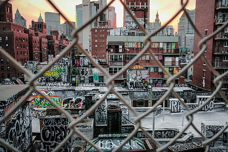 buildings with graffiti artworks through chain-link fnce thumbnail