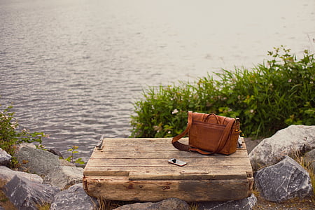 crossbody bag on brown crates near body of water thumbnail