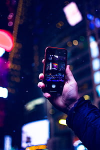 bokeh photography of person's hand holding smartphone taking photo of buildings thumbnail