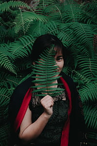 woman standing near tree covering her face using leaf thumbnail