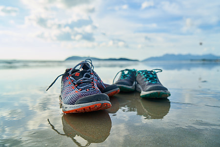 two pairs of assorted-color shoes on body of water under white clouds thumbnail
