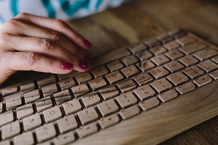 Closeup of female hands typing text on a wireless wooden keyboard thumbnail