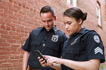 police woman holding phone near man thumbnail