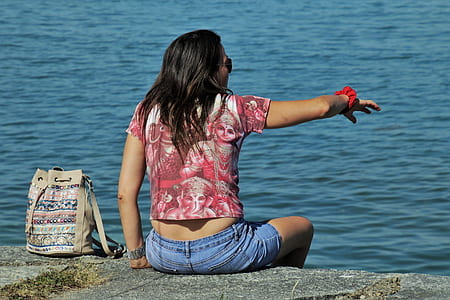 woman sitting beside body of water thumbnail
