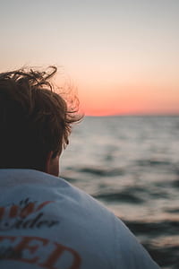 person in white and red shirt looking in front of blue sea water thumbnail