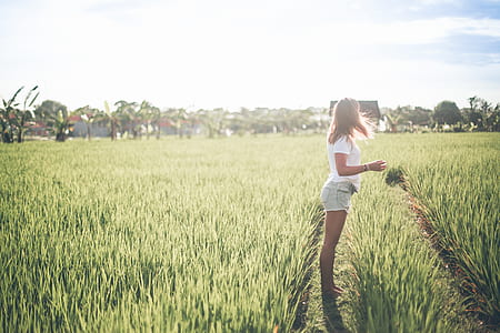 woman standing on green grass field during daytime thumbnail