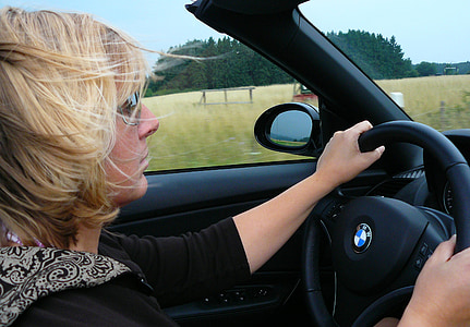 woman in black shirt driving a BMW car near green fields thumbnail