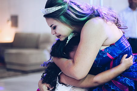 woman in blue dress hugging girl in white dress thumbnail