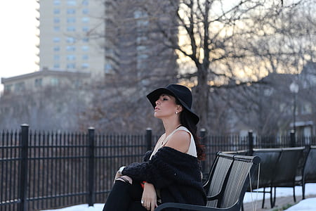 woman in white sleeveless dress and black top with hat sitting during daytime thumbnail