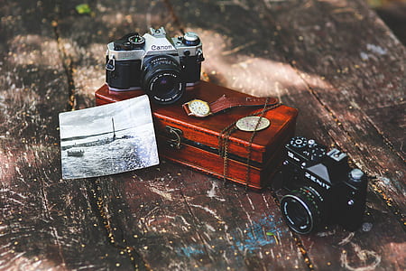 two black and gray DSLR camera on brown table thumbnail