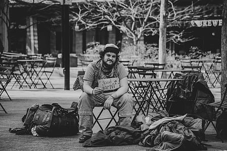 man sitting beside round steel table in grayscale photography thumbnail