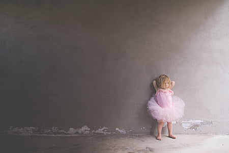 girl wearing pink dress standing on floor while leaning on wall thumbnail