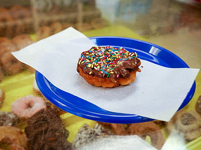 Cake donut with sprinkles and chocolate icing on a blue plate. thumbnail