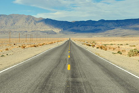 black concrete road near high mountains under blue and white sky at daytime thumbnail