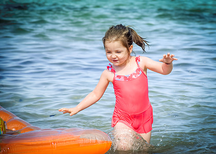 girl wearing camisole walking on blue body of water during daytime thumbnail