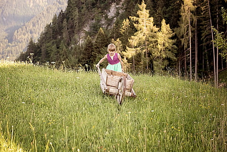 girl pushing a wheelbarrow in forest thumbnail