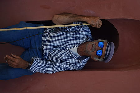 man sitting on brown surface while holding stick thumbnail